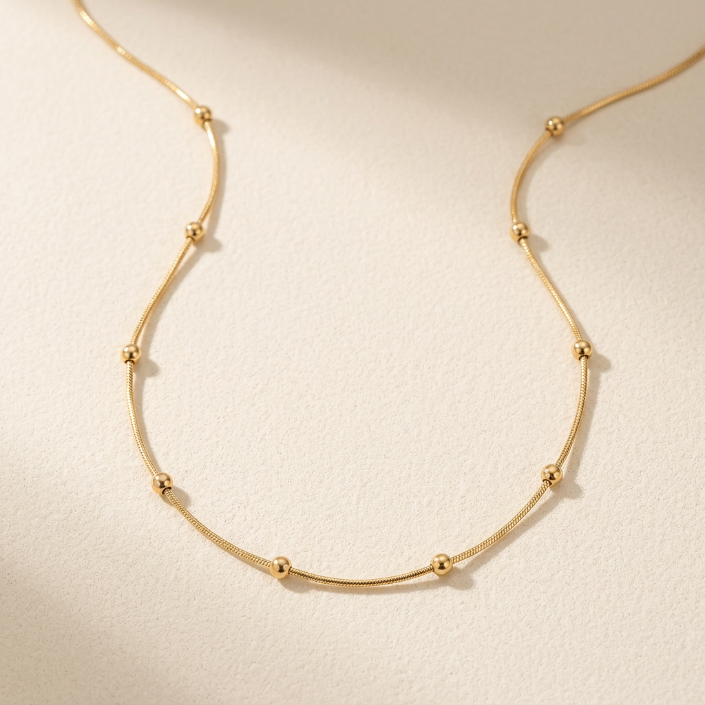 Gold beaded necklace on a warm-neutral background