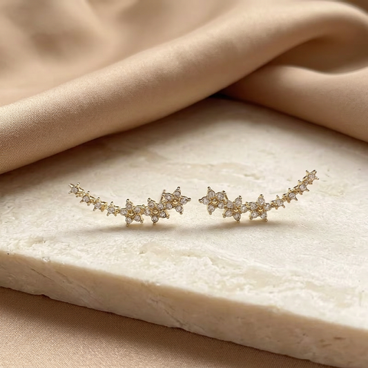 Gold-tone earrings styled on an ivory surface